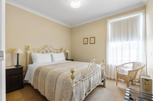 a bedroom with a bed and a chair and a window at The Station in Hunterville