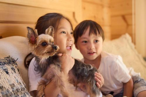 two children sitting on a bed with a small dog at Solana 鴨川 in Kamogawa