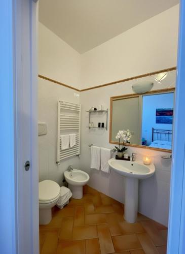 a bathroom with two sinks and a toilet and a mirror at Hotel Ristorante Le Querciolaie dei Ricci in Fonteblanda