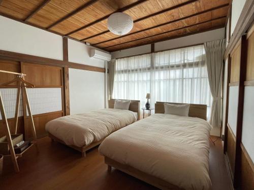 a bedroom with two beds and a window at 国登録有形文化財の宿 Hotel 旧若林邸 in Sado