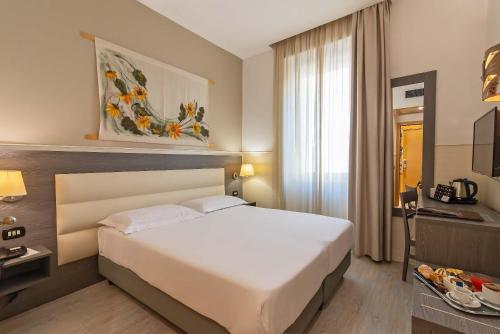 a hotel room with a white bed and a window at Hotel Aphrodite in Rome