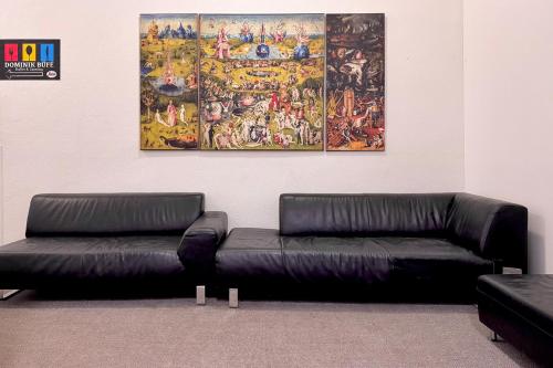 two black leather couches in a room with a painting at Dominik Panzió in Budapest