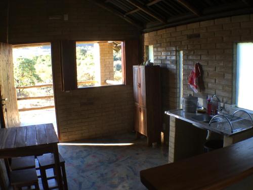 a kitchen with a refrigerator and two windows at Pousada Morro da Baleia in Alto Paraíso de Goiás