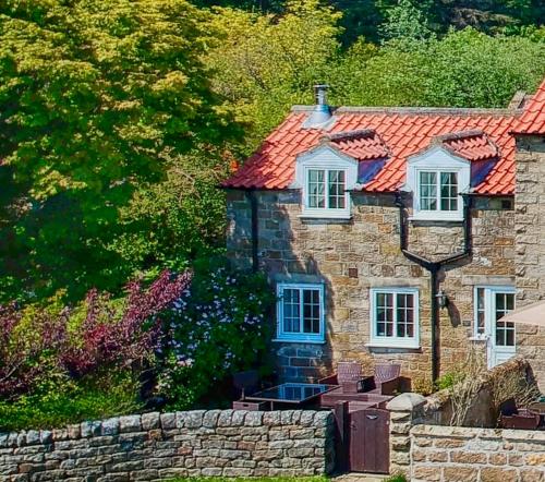an old stone house with a red roof at Smugglers Rock Cottages in Ravenscar