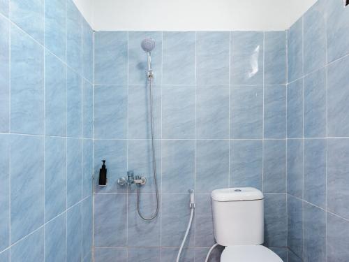 a blue tiled bathroom with a shower with a toilet at RedDoorz Plus Ciapus Bogor in Cimanglid