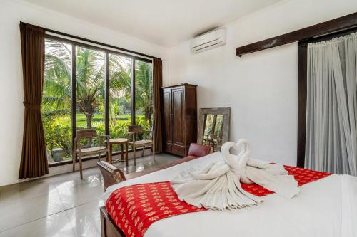 a bedroom with a bed with a red and white blanket at Sunset Pandawa Villa in Ubud