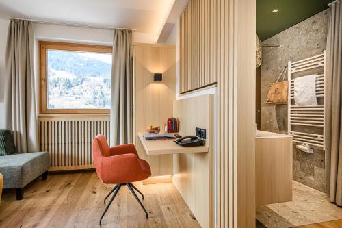 a room with a desk and a chair and a window at Impuls Hotel Tirol in Bad Hofgastein