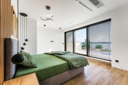 a bedroom with a green bed and a large window at Villa K&L Pasohlávky in Pasohlávky