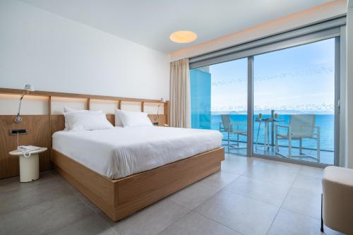 a bedroom with a bed and a view of the ocean at Kos Aktis Art Hotel in Kos