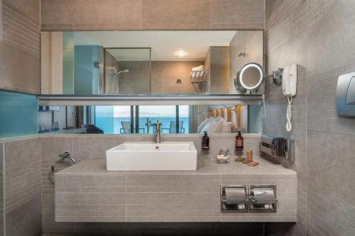 a bathroom with a sink and a mirror at Kos Aktis Art Hotel in Kos