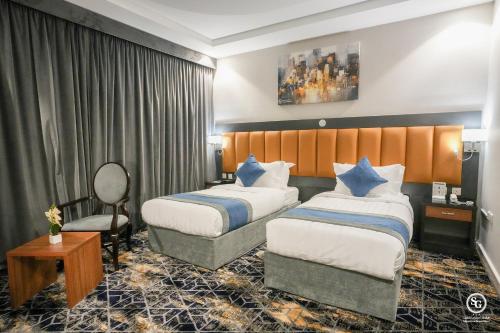 a hotel room with two beds and a chair at فندق امضاء النزيل المدينة المنورة in Medina