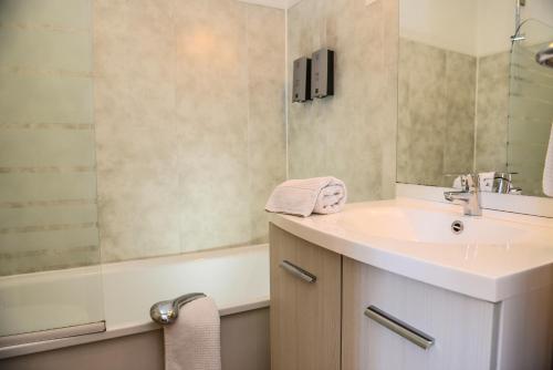 a bathroom with a sink and a mirror and a tub at Logis Hostellerie du Neez in Gan