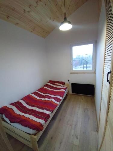 a bed sitting in a room with a window at Sosnowy Zakątek, Laskowo in Laskowo