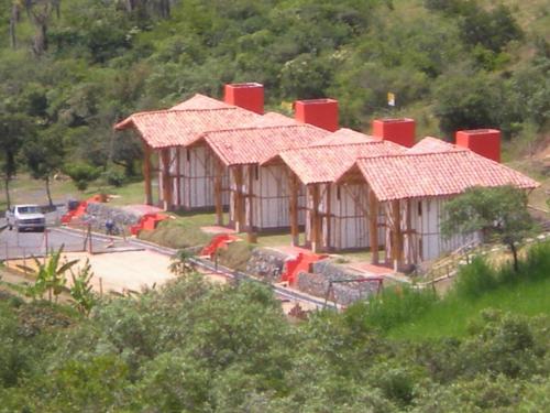 a group of huts with red roofs in a park at Hotel La Montoya in Curití