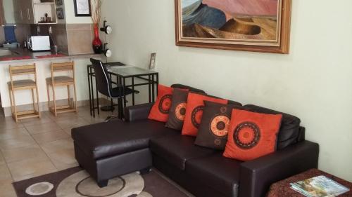 a living room with a black couch with orange pillows at Wilger Guesthouse in Centurion