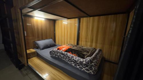 a small bed in a small room with wooden walls at Dostel in Bhowāli