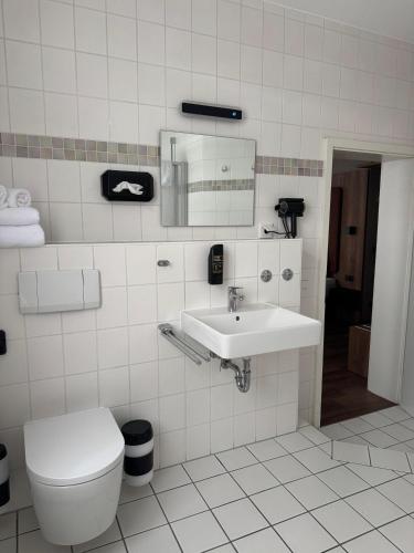 a white bathroom with a toilet and a sink at Hotel und Restaurant Hohe Schule in Herborn