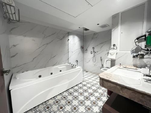 a white bathroom with a tub and a sink at Emerald Luxe A Boutique Hotel Chandigarh Mohali in Mohali