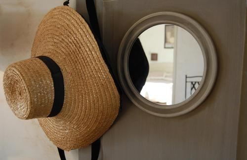 a straw hat hanging on a wall with a mirror at Cyprès du Paradis à Gordes in Gordes