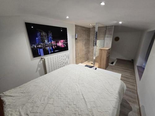 a bedroom with a large bed with a tv on the wall at Petit studio fief in Le Fief-Sauvin