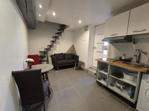 a kitchen and living room with a couch and stairs at Petit studio fief in Le Fief-Sauvin