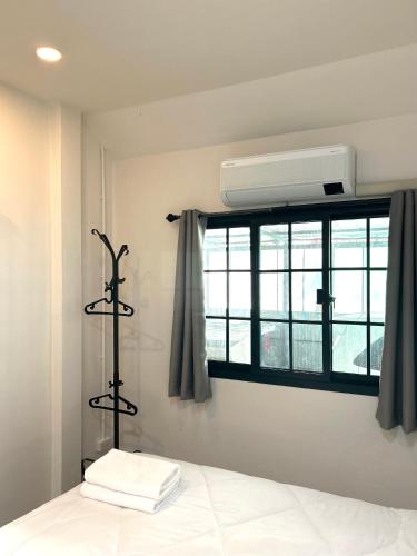 a bedroom with a bed and a window with a air conditioner at Airport Cozy House - Suvarnabhumi in Samutprakarn