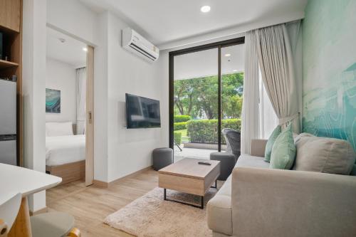 a living room with a couch and a bedroom at Skypark Aurora in Laguna by Banyan Living in Thalang