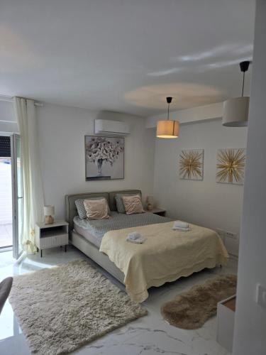 a white bedroom with a bed and a rug at Studio apartman Carera Deluxe in Vinkovci