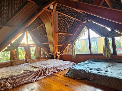 a bedroom with two beds in a room with windows at Đà Lạt Củi Homestay in Da Lat