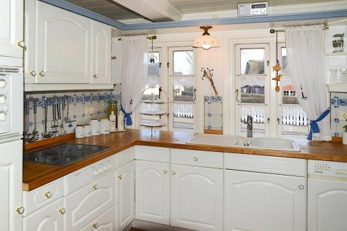 a kitchen with white cabinets and a sink and windows at Ferienwohnung in Oevenum auf Foehr in Oevenum