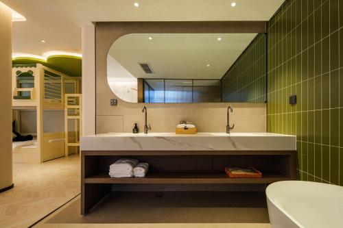 a bathroom with a sink and a mirror and a tub at Panda Sleepy Hotel（Chengdu Panda Base) in Chengdu