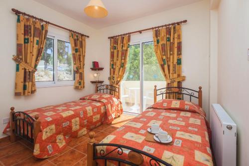 a bedroom with two beds and a window at Thekla Court in Polis Chrysochous
