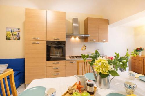 a kitchen with wooden cabinets and a table with flowers at Piazza Verdi-Roseto Vacanza in Roseto degli Abruzzi