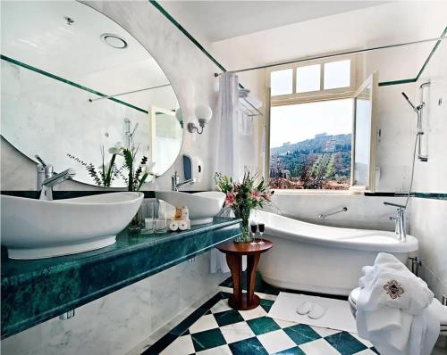 a bathroom with two sinks and a tub and a window at The Colony Hotel in Haifa