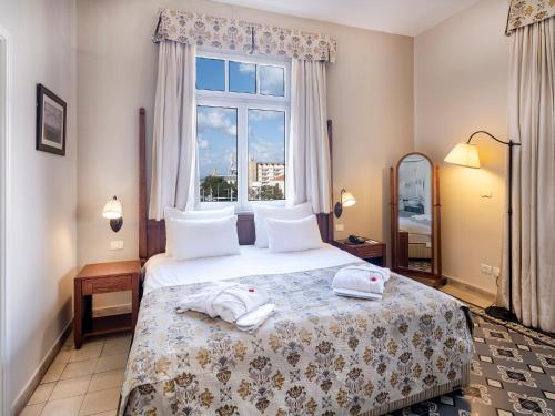 a bedroom with a bed with two towels on it at The Colony Hotel in Haifa