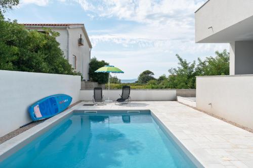 a swimming pool with two chairs and an umbrella at Premium Apartment Obatnice with Pool in Povljana