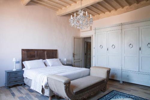 a bedroom with a bed and a chair and a chandelier at Wp Relais Mazzini in Montalcino