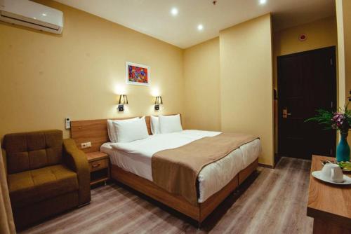 a hotel room with a bed and a chair at Hotel Date in Tbilisi City
