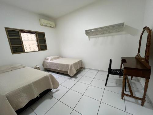 a bedroom with two beds and a desk and a piano at Casa aconchegante com 2 quartos, próximo ao Centro, UFU, Center Shopping e Convention, Hospitais e Aeroporto in Uberlândia