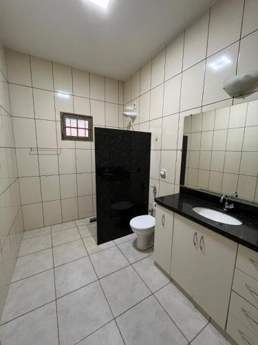 a bathroom with a toilet and a sink at Casa aconchegante com 2 quartos, próximo ao Centro, UFU, Center Shopping e Convention, Hospitais e Aeroporto in Uberlândia