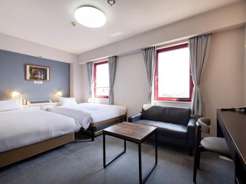 a hotel room with two beds and a couch at KOKO STAY Miyakonojo in Miyakonojō