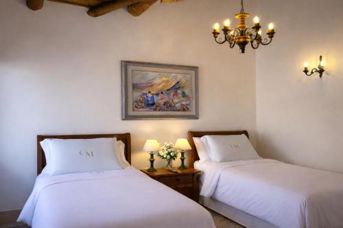 two beds in a room with a chandelier at Casa Malinalco Hotel Boutique & Restaurante in Sotosalbos