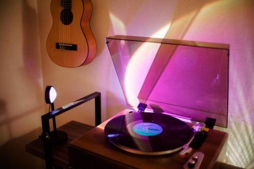 a record player and a lamp on a table with a guitar at MINIMAL SHIMOKITA Stylish Loft or Studio Apt in Tokyo