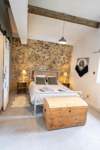 a bedroom with a bed and a stone wall at Le refuge in Marsalès