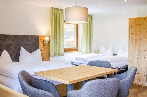a room with two beds and a table and chairs at Pension Edelweiß in Sankt Johann im Pongau