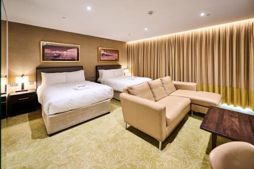 a hotel room with two beds and a couch at Genting Hotel & Spa at Resorts World Birmingham in Bickenhill