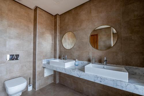 a bathroom with two sinks and a toilet and mirrors at Villa Palms de l'Atlas in Marrakesh