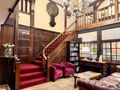 a living room with a staircase and red chairs at The Angel Posting House & Livery in Guildford