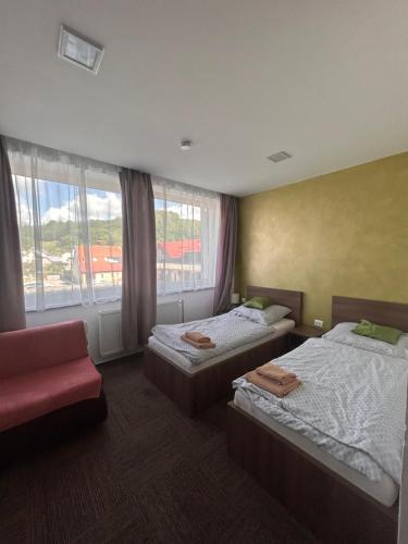 a room with two beds and a chair and a window at Penzion Teplanka in Považská Bystrica