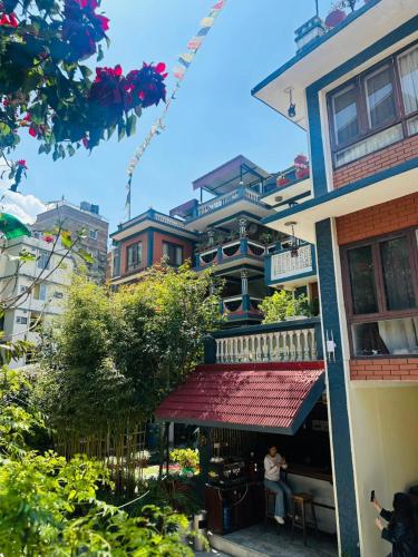 a woman sitting on a balcony of a building at Boudha Orange Hotel in Kathmandu